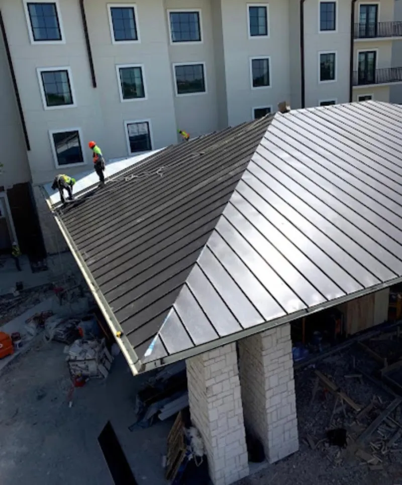 Crew installing standing seam metal roof panels on a commercial project in Eastmont